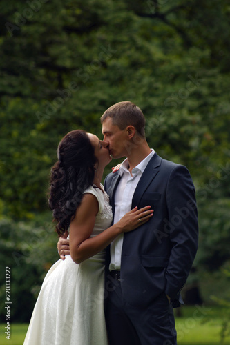 Kiss of the loving newlyweds in the summer in the park