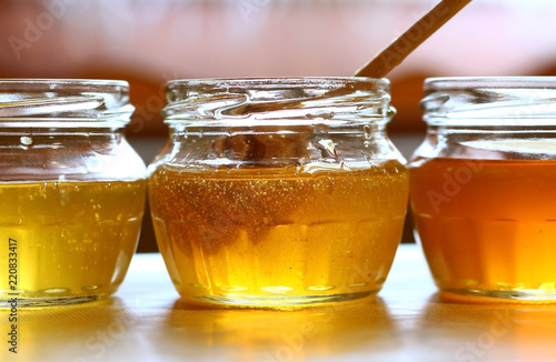 three cans of honey of different colors with a wooden spoon