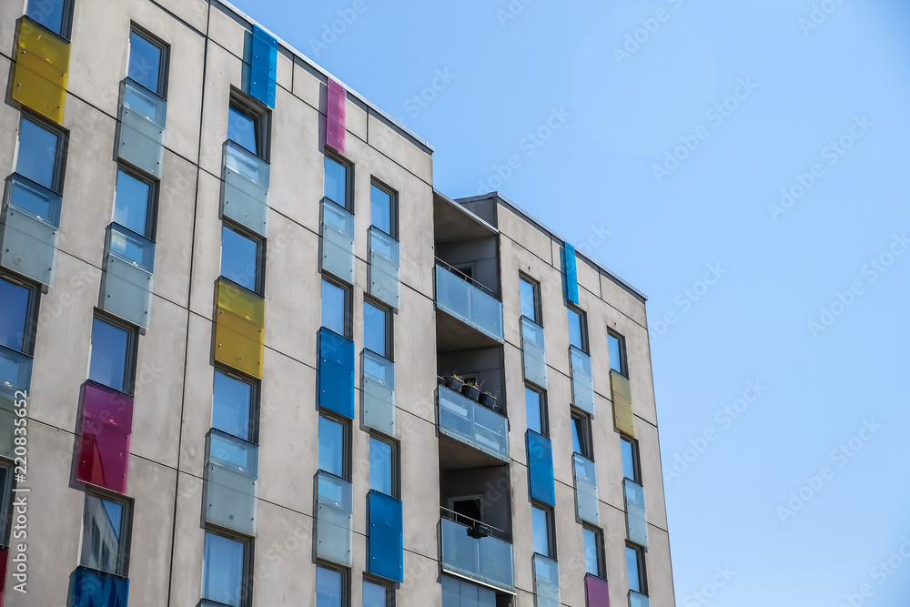 Fototapeta premium Colourful glass windows of a modern building against a blue sky