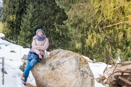 An elderly woman in the mountains in winter. Pensioner resting in nature
