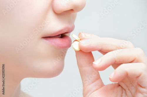 Girl with a pill in her hand, open mouth. Close-up.
