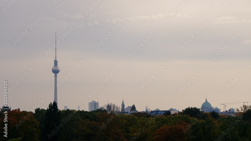 Obraz premium View over Berlin skyline including the Fernsehturm TV tower, with dusky overcast sky and autumnal trees