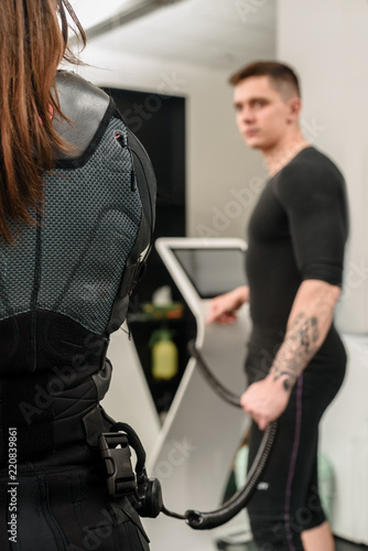 Male trainer connecting suit with EMS machine before training