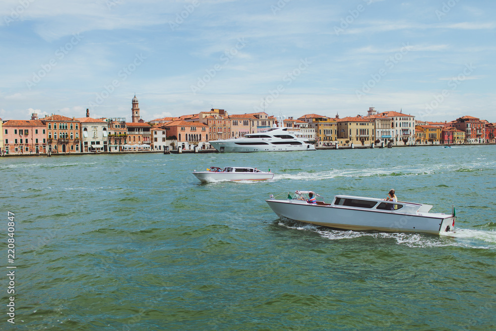 Venetian channel view at the city of urban architecture, boats, buildings, pier, yacht, transport of Venice