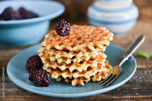 Round waffles with fresh blackberries and icing sugar on wooden background rustic