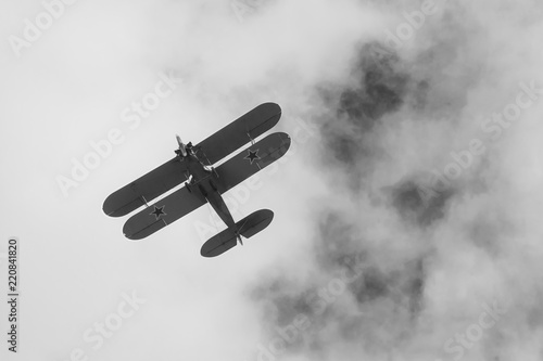 Black and white photo of biplane on airshow in Krakow, Poland. Historical war plane, with stars on wings, monochrome design.