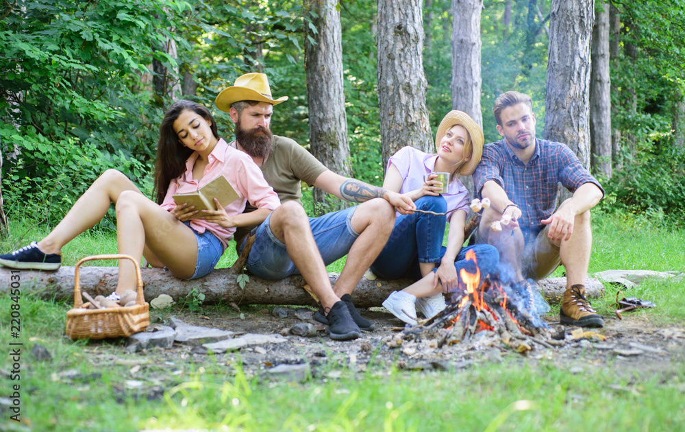 Youth hiking vacation. Hikers spend leisure in forest nature background. Hikers organized quick picnic to eat and relax. Hike picnic ideas. Hikers sit near campfire relaxing while wait roasting food Youth hiking vacation. Hikers spend leisure in forest nature background. Hikers organized quick picnic to eat and relax. Hike picnic ideas. Hikers sit near campfire relaxing while wait roasting food