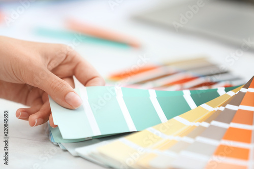 Woman with paint color palette samples at table, closeup photo