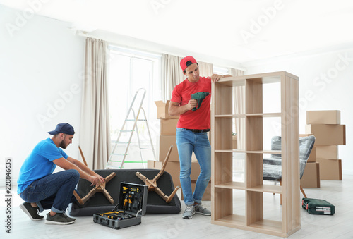 Tablou pe pânză Male movers assembling furniture in new house