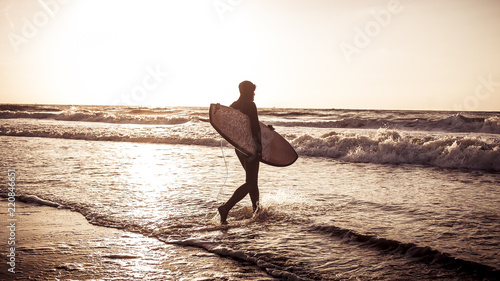 surfer is walking into ocean photo