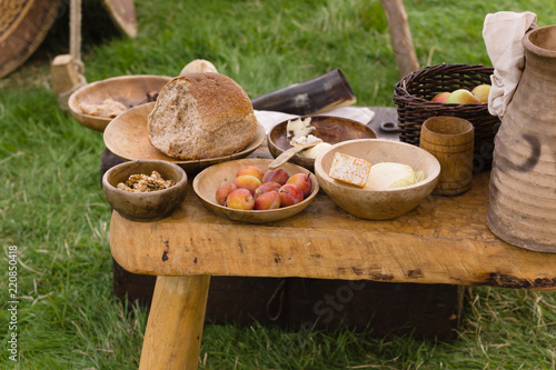 Typical selection of Medieval food including bread, butter, cheese, fruit and nuts served in wooden bowls or trenchers