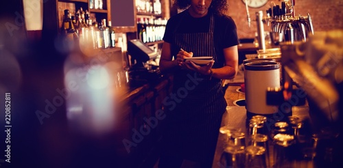 Young waiter writing on diary photo