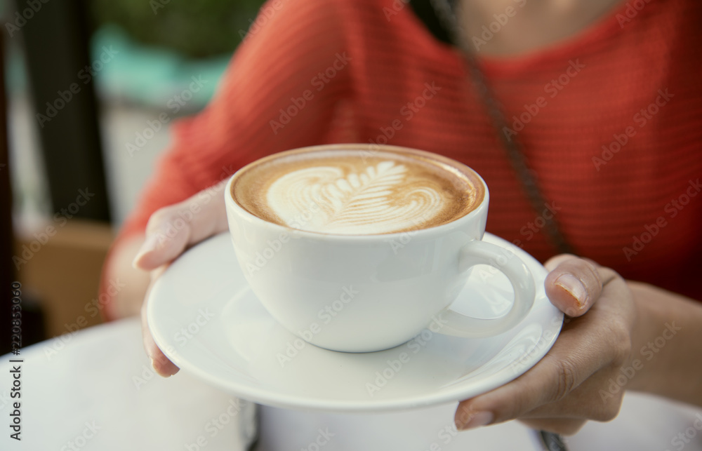 Hand holding latte or Cappuccino with frothy foam, coffee cup top view in cafe. Hand holding latte or Cappuccino with frothy foam, coffee cup top view in cafe.
