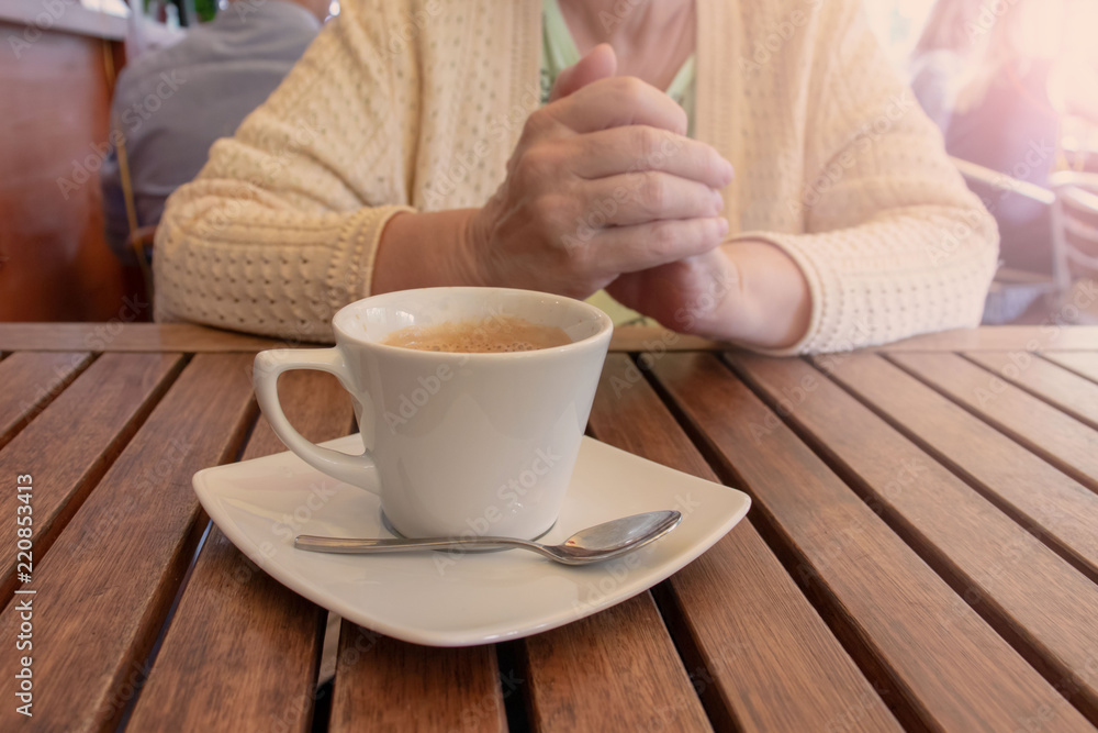 An elderly woman sitting by the table with a cup of coffee in a restaurant. An elderly woman sitting by the table with a cup of coffee in a restaurant.