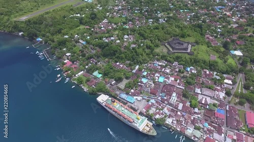 Drone shot of Pelni ship harboring in Banda islands port. Fort Belgica and airport strip visible in background. photo