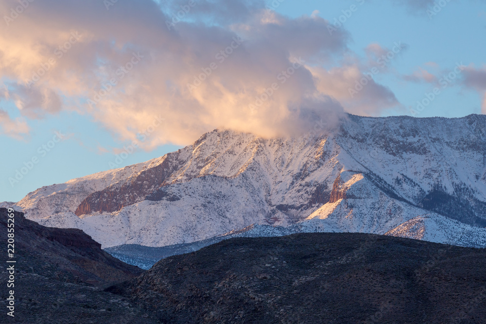 Sunset image of snow covered mountain partially covered by clouds