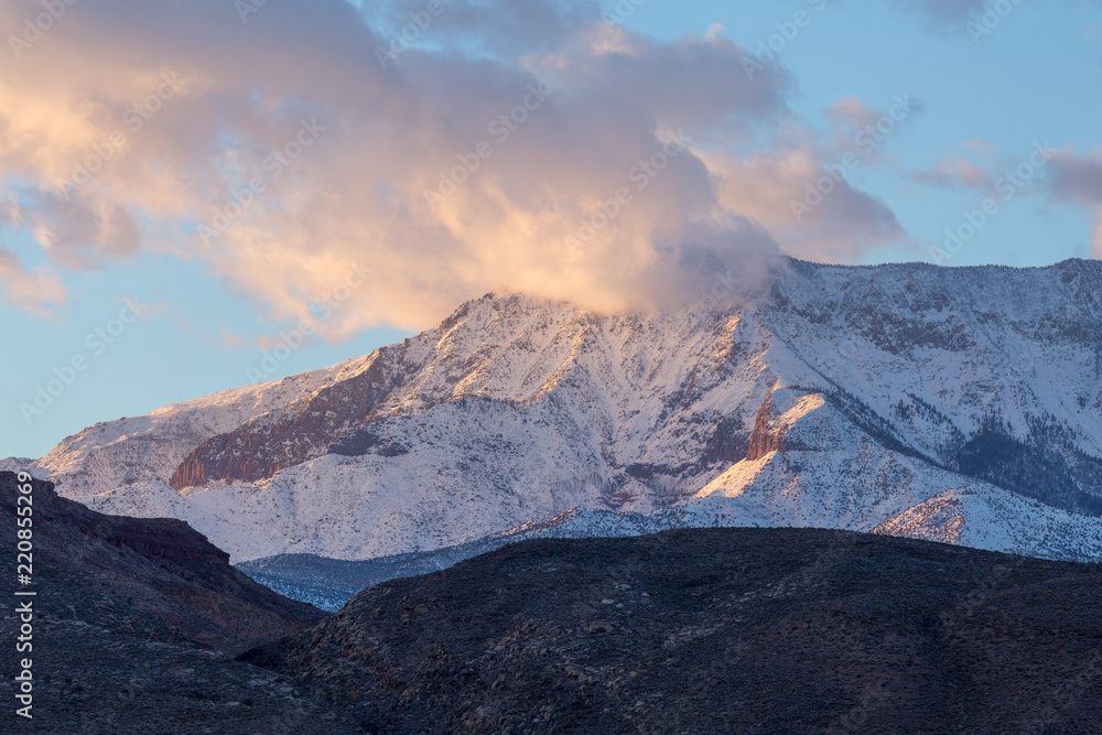 Obraz premium Sunset image of snow covered mountain partially covered by clouds