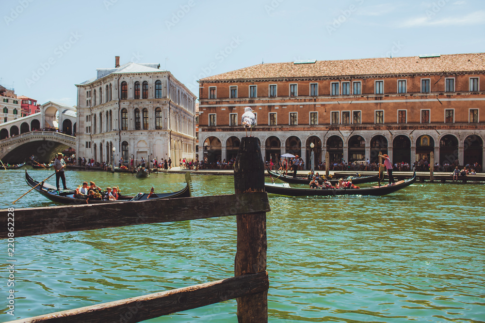 venice channel with gandols with tourists and gondoliers around the beautiful architecture of a sinking city