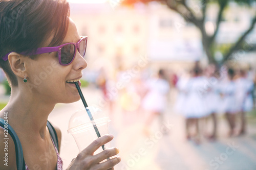 A girl in glasses walks around the city and drinks morning coffee.