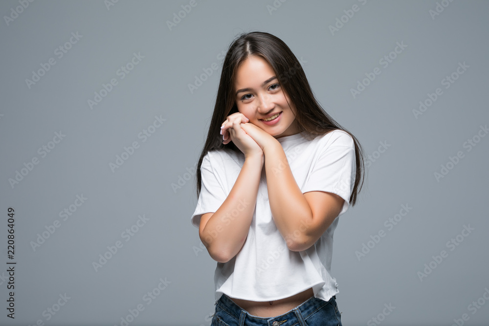 Sensual pleased smiling asian woman posing and looking away over gray background Sensual pleased smiling asian woman posing and looking away over gray background