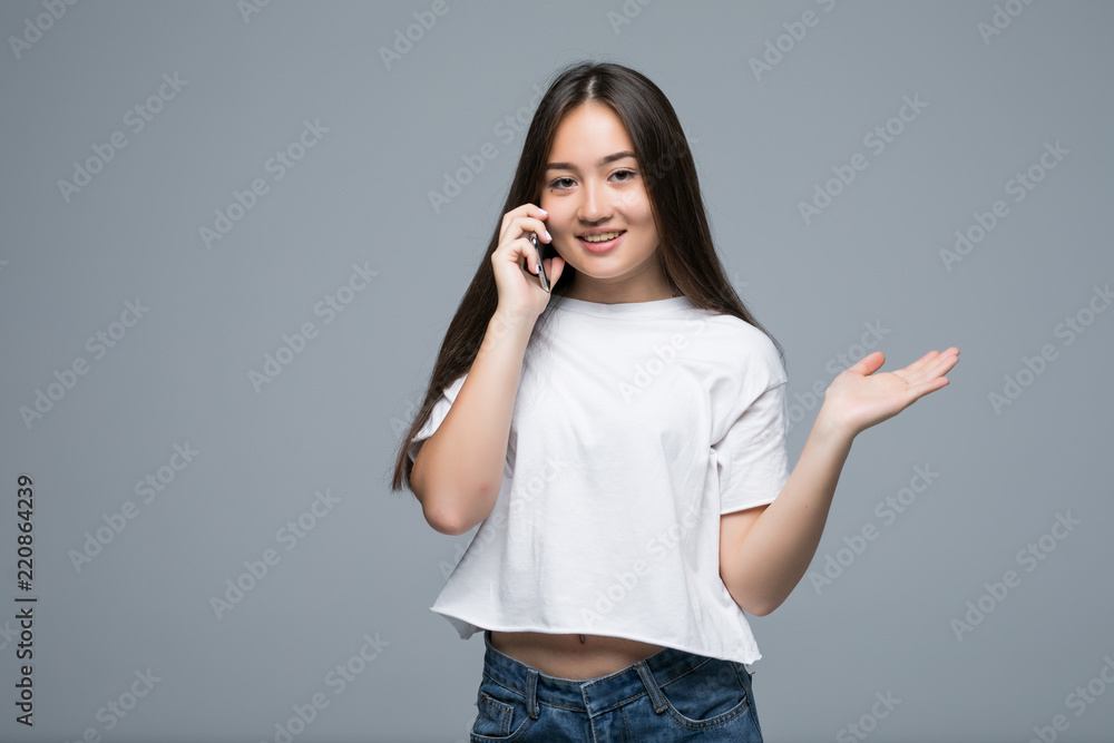 Young asian girl talk to mobile phone isolated on gray background Young asian girl talk to mobile phone isolated on gray background