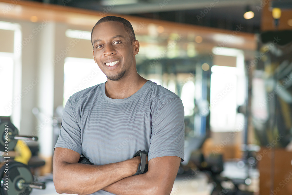 Smiling sporty black man standing with his arms crossed in gym and ...