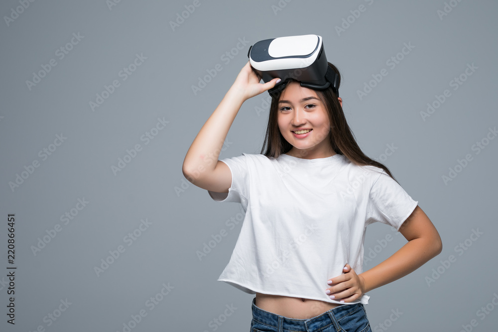 Young asian girl watching VR though and hand touch on air on gray background Young asian girl watching VR though and hand touch on air on gray background
