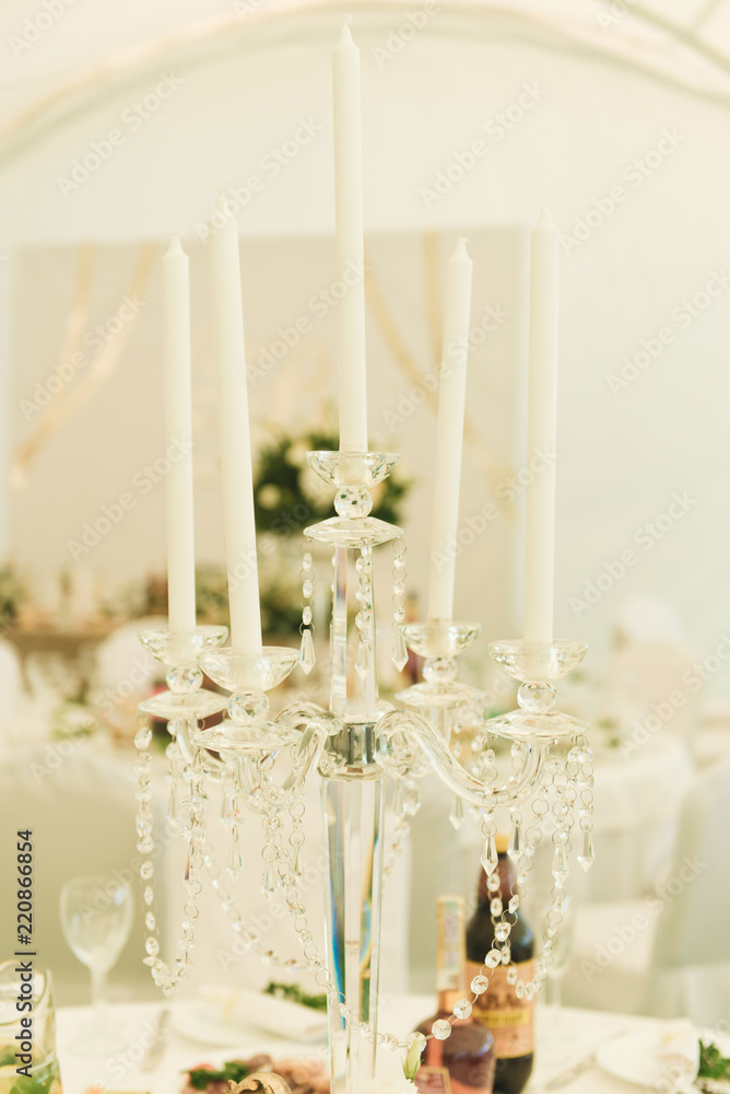 Arch on festive table newlyweds covered with a tablecloth and decorated with composition of flowers and greenery, candles in the wedding banquet hall. Wedding party in tent.
