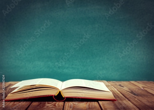 Open book on floor in front of blackboard