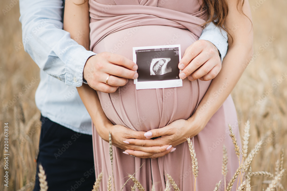 Close-up of unrecognizable pregnant woman with ultrasound picture in hand