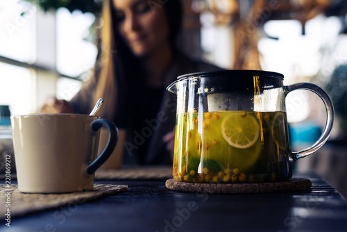 Bild auf Leinwand close-up of Cup and glass teapot with sea buckthorn tea with lemon and herbs, wo