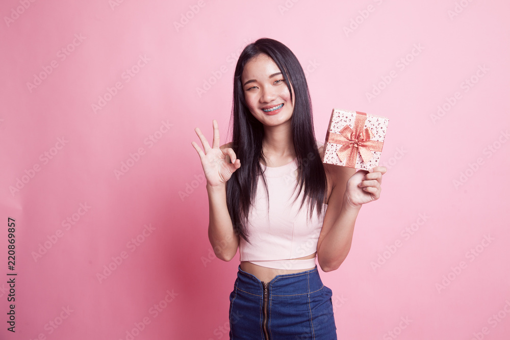 Young Asian woman show OK with a gift box. Young Asian woman show OK with a gift box.
