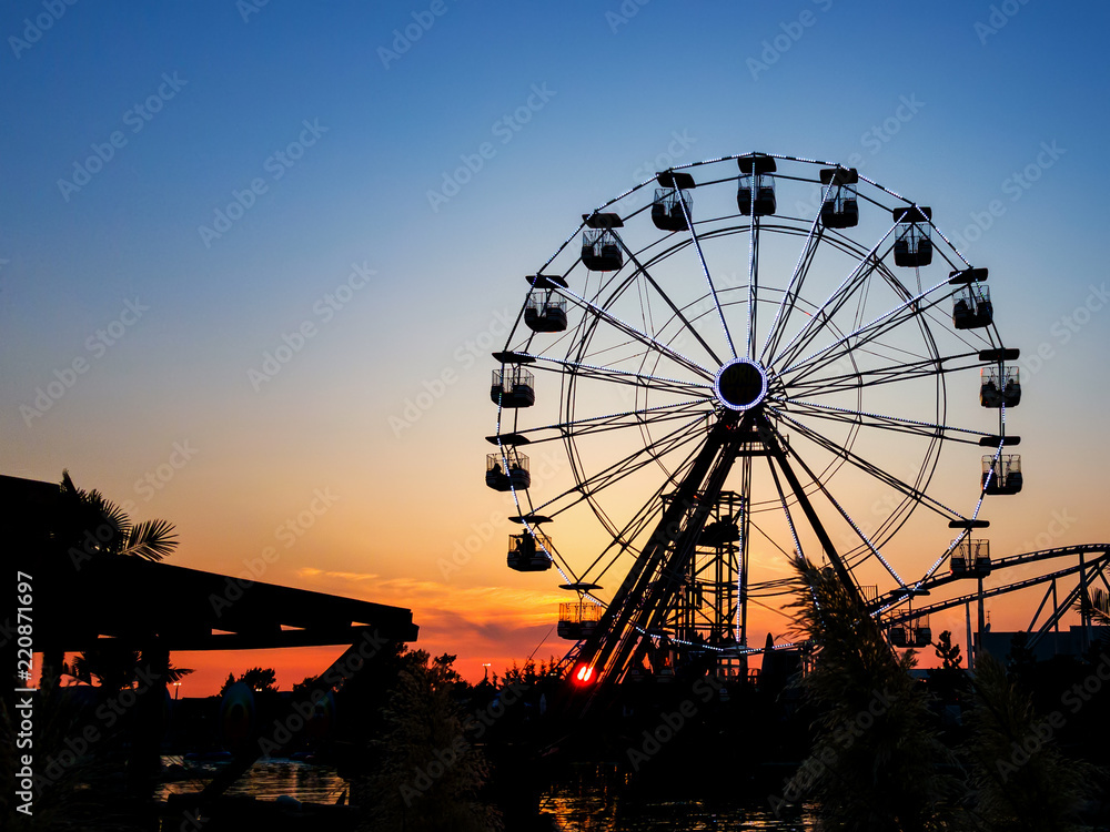 Ferris wheel in sunset.  Big wheel with cabins