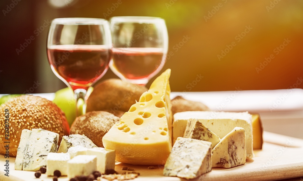 Assortment of cheese on board and two glasses of wine Assortment of cheese on board and two glasses of wine