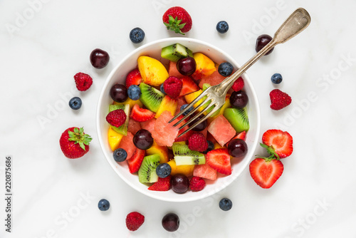 fruit salad with watermelon, strawberry, cherry, blueberry, kiwi, raspberry and peaches with fork in a bowl