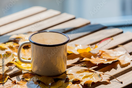 metal cup of coffee or tea with leaves on table at balcony.