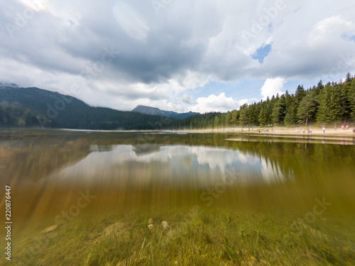 Crystal clear forest lake surrounded with pine trees.