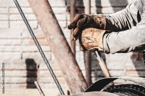 Worker hands pulling the lever of a pile driver (bate-estaca). Construction worker. Two hands holding a lever. Worker hands wearing worn out gloves triggering a motor that moves steel cables.