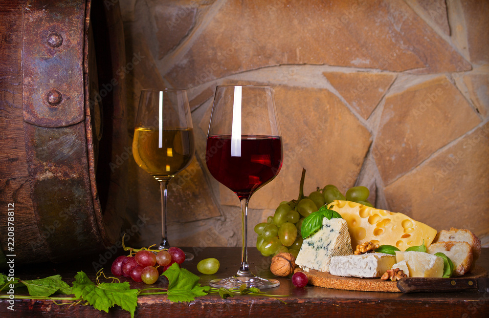 Red and white wine with cheese and grapes beside old cask in wine cellar. Glasses and bottles of wine