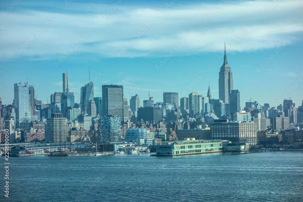 Famous view on New York Midtown Waterfront pier in Manhattan through the Hudson river. Blue sky and clouds background. Famous view on New York Midtown Waterfront pier in Manhattan through the Hudson river. Blue sky and clouds background.