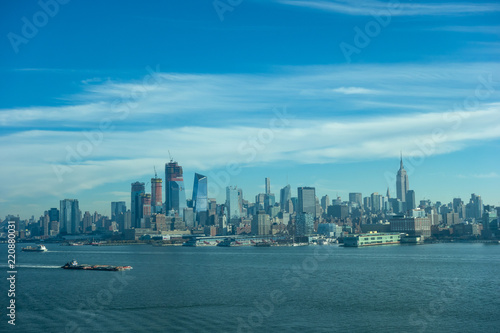 Famous view on New York Midtown Manhattan through the Hudson river. Blue sky and clouds background.