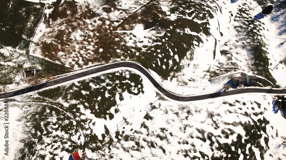 Road winds through the hills partially covered with snow.