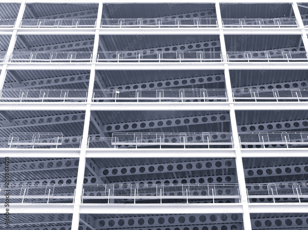 A monochrome blue tinted looking upwards view of large modern commercial building under construction with steel beams and girders A monochrome blue tinted looking upwards view of large modern commercial building under construction with steel beams and girders