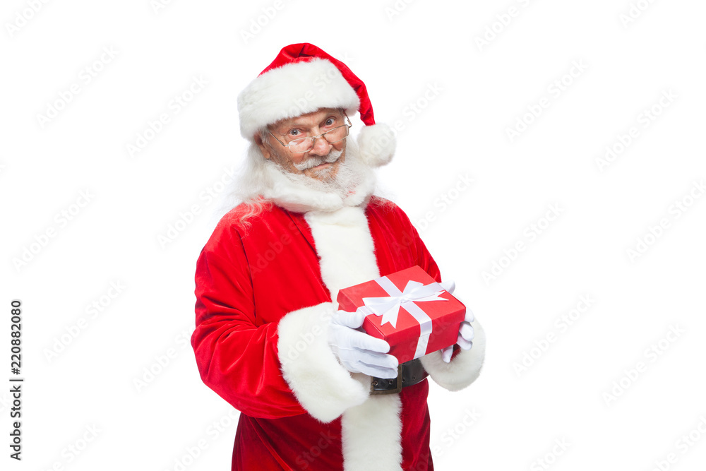 Christmas. Smiling Santa Claus in white gloves is holding a gift red box with a bow. Pointing at the gift. Isolated on white background. Christmas. Smiling Santa Claus in white gloves is holding a gift red box with a bow. Pointing at the gift. Isolated on white background.