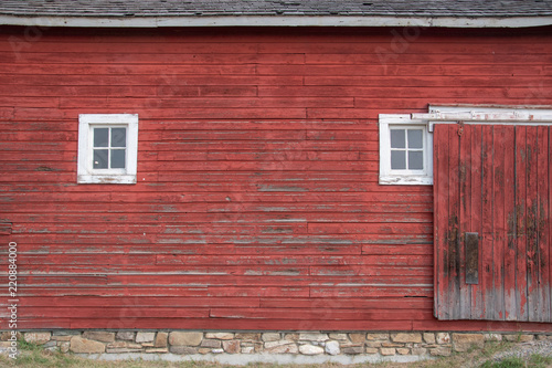 Side of an old red barn with white framed square windows and sliding door