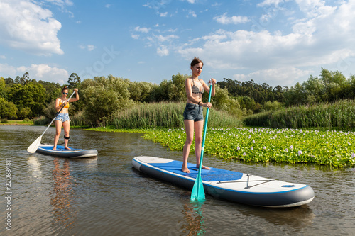 Two women stand up paddleboarding