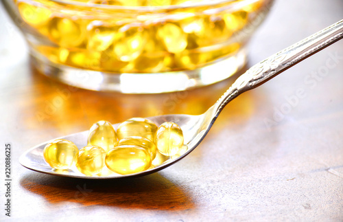 Fish oil capsules on wooden background, vitamin D supplement, selective focus, copy space for text.