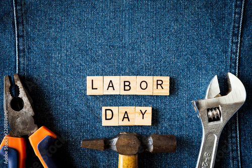 USA Labor day concept, First Monday in September. Different kinds on wrenches, handy tools, America flag and wooden tag on blue jeans background.
