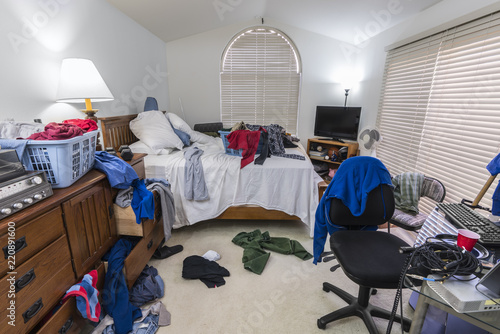 Canvas Print Messy, cluttered teenage boy's bedroom with piles of clothes, music and sports equipment