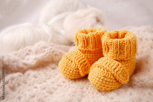 close-up of baby knitted shoes on soft crocherting background